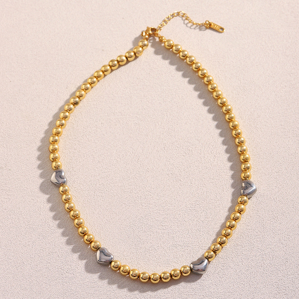 Collar de acero inoxidable minimalista con forma de corazón, chapado en oro de 18 quilates y detalle de cuentas.