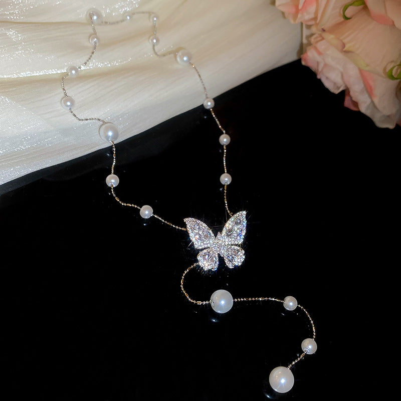 Collana con ciondolo a farfalla in zirconi placcato oro, stile dolce e minimalista, con inserti in perle e dettagli sfrangiati da donna