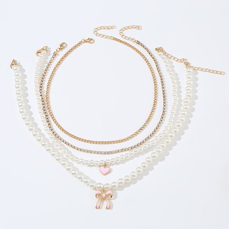 Set di collana con ciondolo a fiocco e cuore stile dolce per bambini con accenti di perle e perline infilate a mano su catena in resina