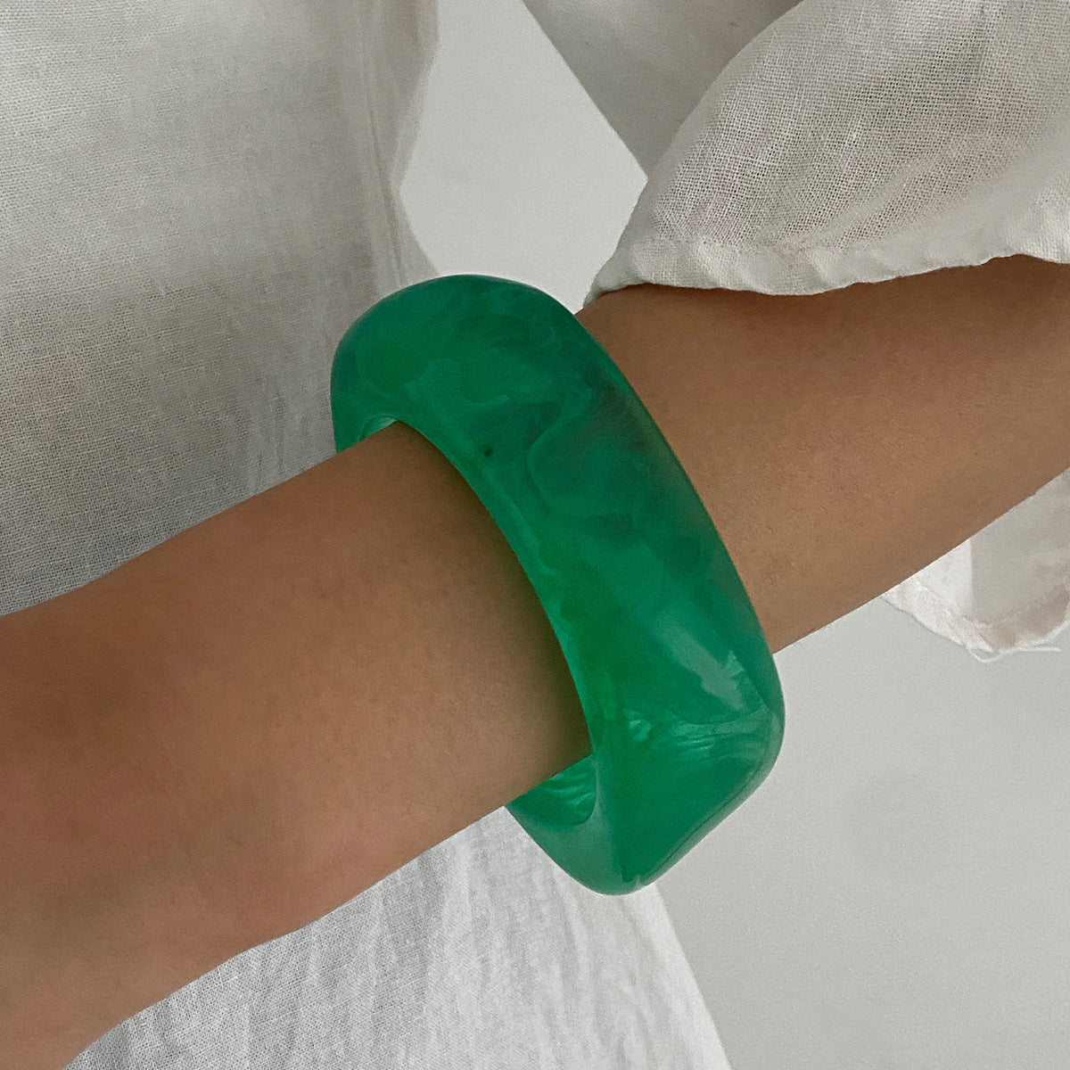 Bracciale minimalista in resina con forme geometriche irregolari, effetto sfumato e finitura placcata