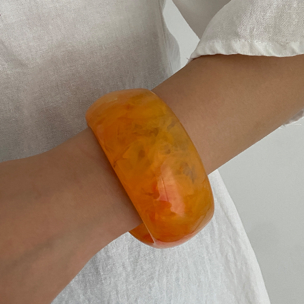 Bracciale minimalista in resina con forme geometriche irregolari, effetto sfumato e finitura placcata
