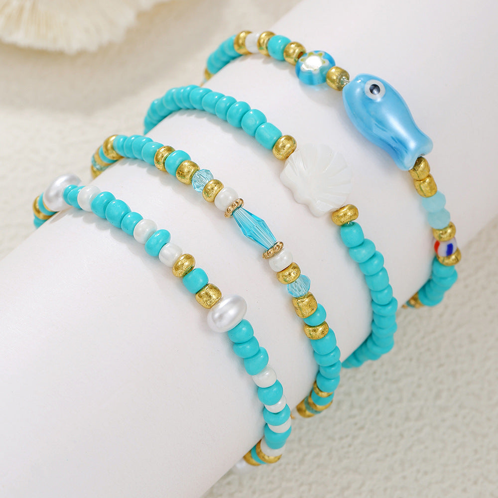 Pulsera bohemia de vacaciones en la playa con abalorios de peces y conchas de cerámica en un hilo de cuentas multicapa