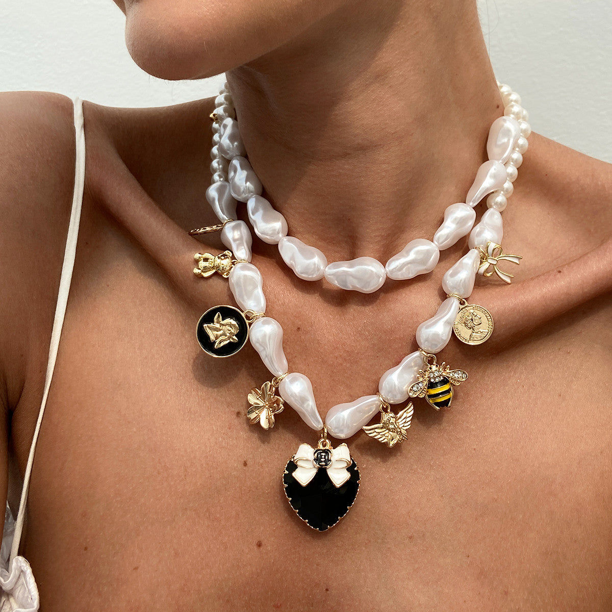 Collana con pendente a forma di ape esagerata a cuore e forma geometrica con base in lega placcata, perle imitate e intarsi in strass acrilici per donna