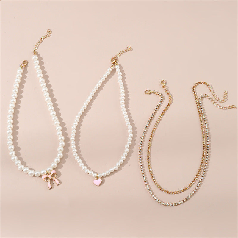 Set di collana con ciondolo a fiocco e cuore stile dolce per bambini con accenti di perle e perline infilate a mano su catena in resina