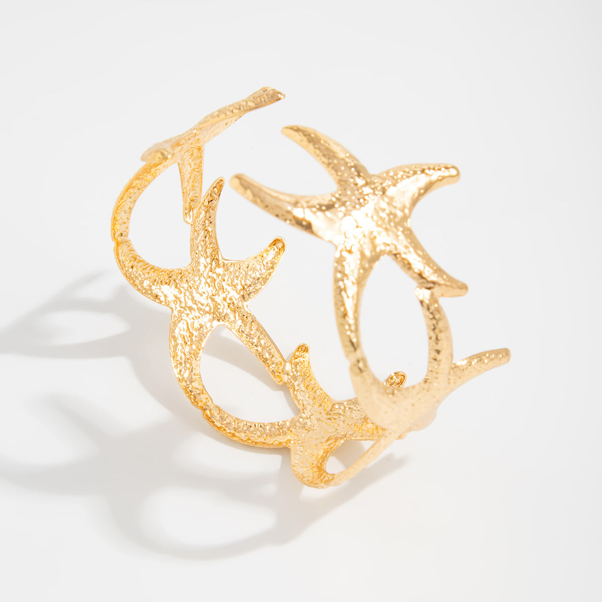 Pulsera rígida abierta con forma de estrella estilo vacaciones en metal chapado con superficie texturizada y diseño inspirado en el océano