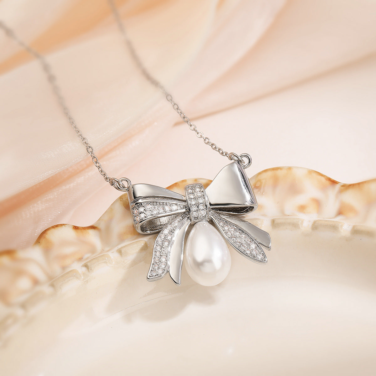 Collana girocollo da donna con ciondolo a fiocco placcato in oro 18 carati su base in rame, con zirconi e perle.