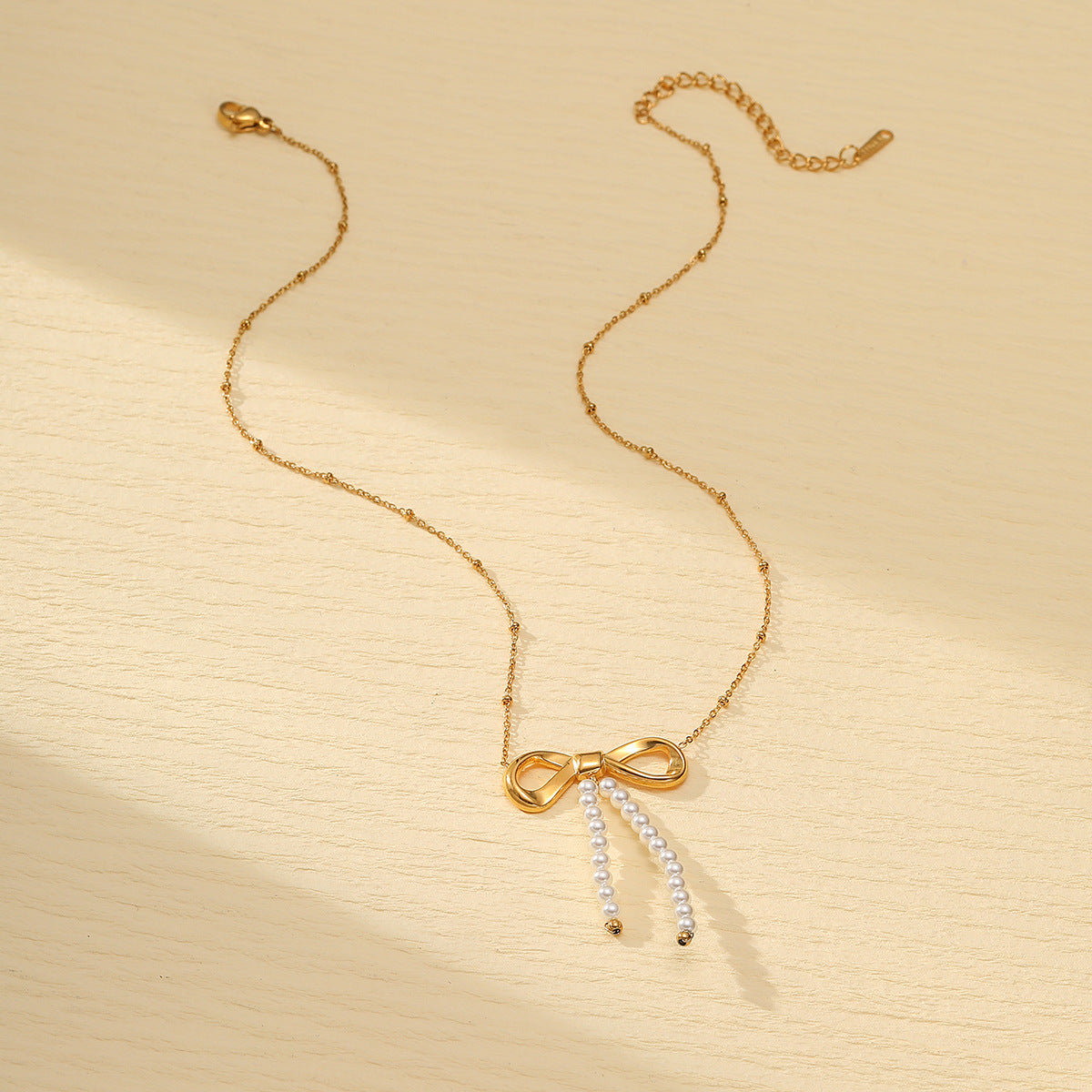 Collar minimalista de acero de titanio con forma de lazo para mujer, con acabado galvanizado y detalle de perlas