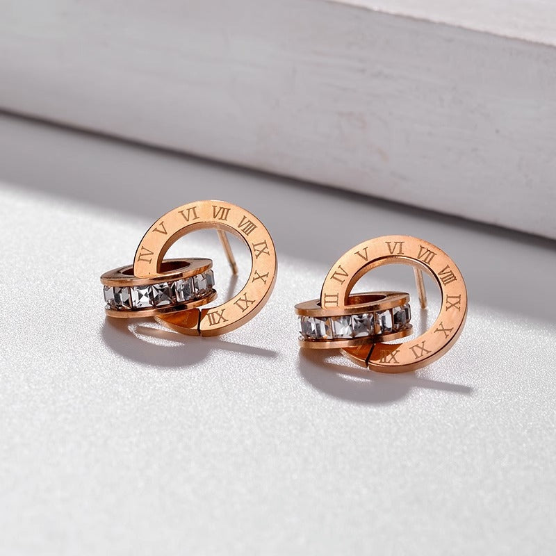 Orecchini a perno da donna in acciaio al titanio lucidato con doppio cerchio romano e strass, placcati in color oro e dallo stile fresco e grazioso