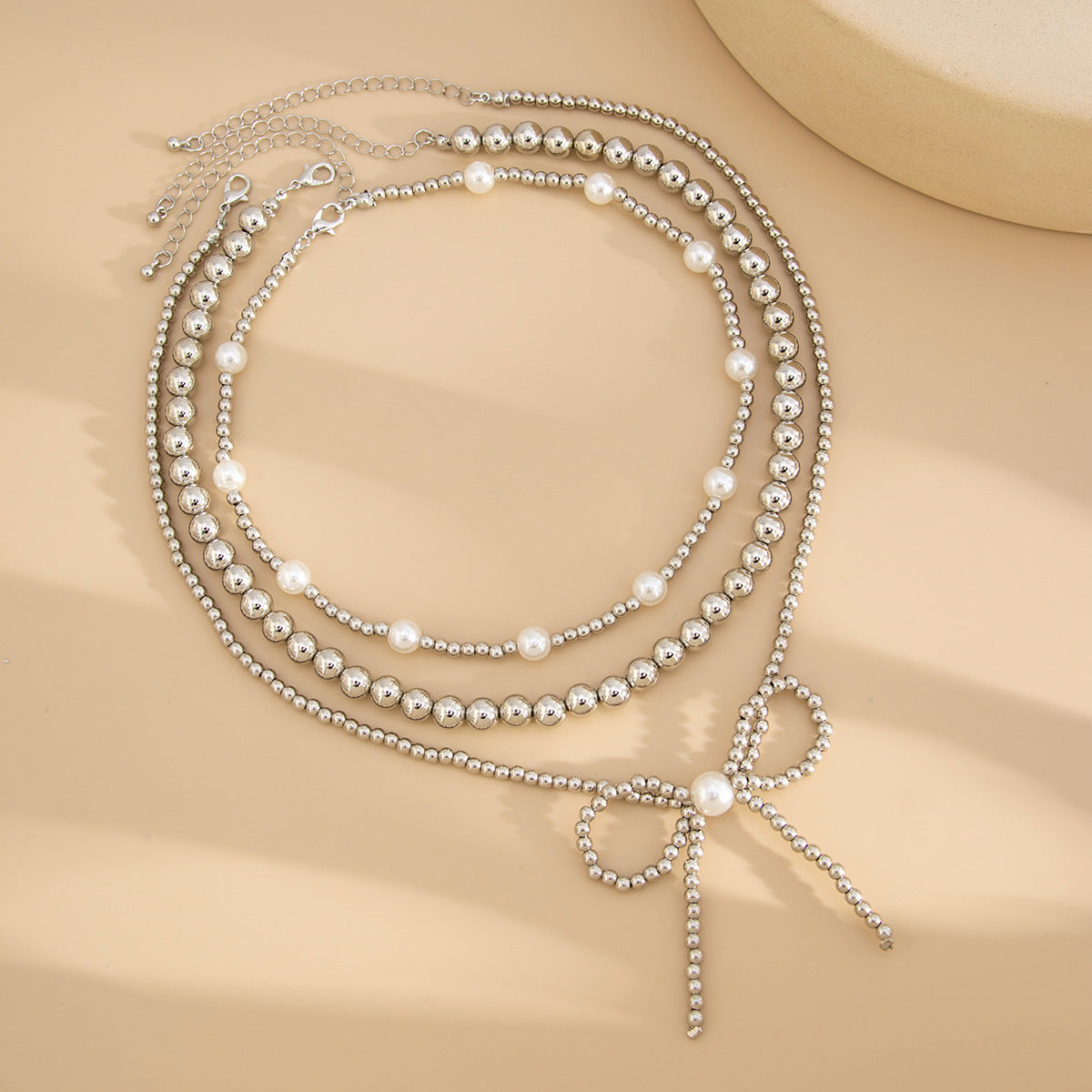 Collana da donna minimalista a forma di fiocco con perle finte e CCB, catena a sfere con perline e design multistrato