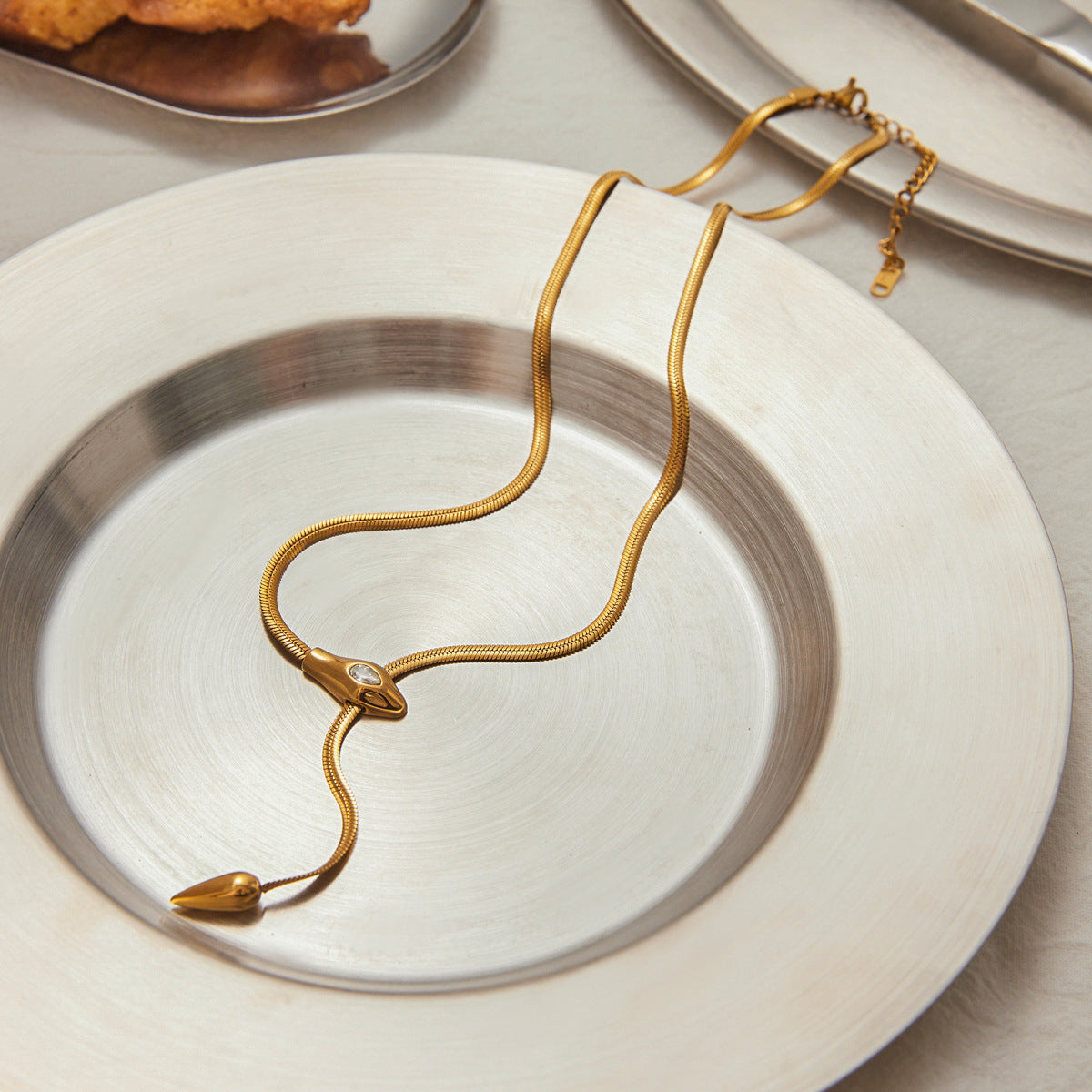 Collana con ciondolo a serpente geometrico in acciaio al titanio con intarsio di strass e finitura placcata per donna