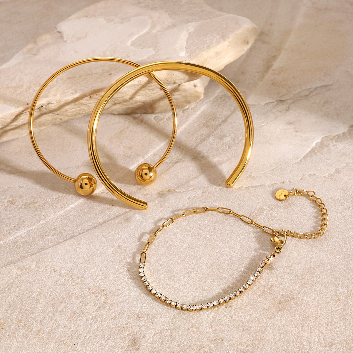 Brazalete minimalista de acero inoxidable con diseño geométrico, detalles de pedrería y acabado chapado