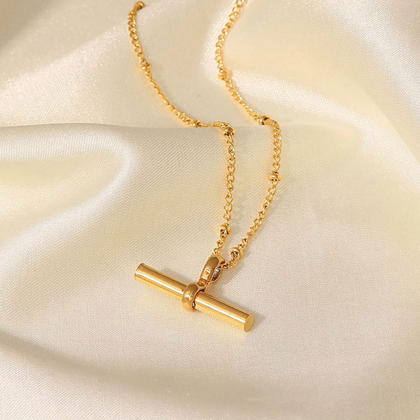 Tobillera minimalista geométrica de titanio y acero con colgante de barra en T chapado en oro de 18K y cadena de cuentas.