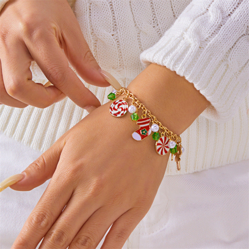 Bracciale artigianale in lega a tema natalizio con ciondolo a forma di Babbo Natale e albero di Natale, perline color caramella, accenti di perle e motivi a fiocco di neve festivi