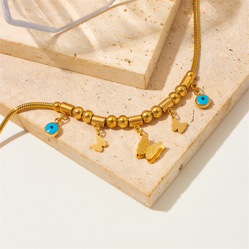 Elegante bracciale con ciondolo a farfalla in acciaio al titanio, perline geometriche e occhi smaltati blu per donna