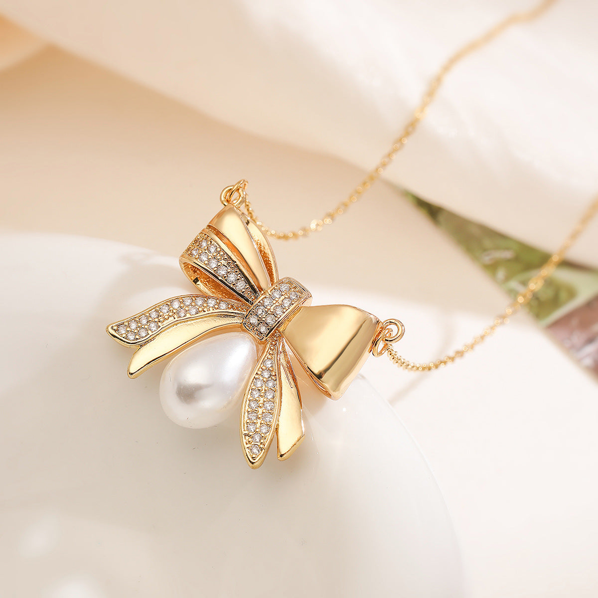 Collana girocollo da donna con ciondolo a fiocco placcato in oro 18 carati su base in rame, con zirconi e perle.