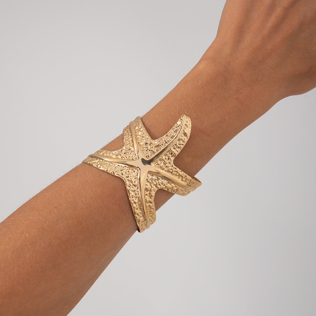 Pulsera metálica con forma de estrella de mar exagerada y acabado galvanizado para un estilo playero y oceánico
