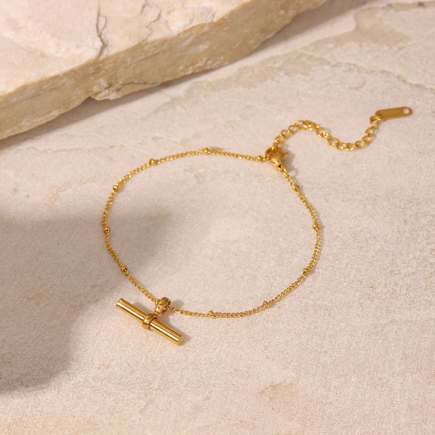 Tobillera minimalista geométrica de titanio y acero con colgante de barra en T chapado en oro de 18K y cadena de cuentas.