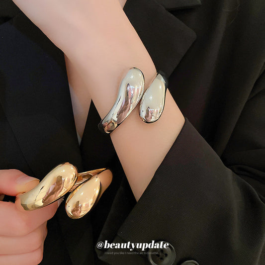 Pulsera de puño ajustable de metal minimalista para mujer con acabado chapado y sutil acento de gota de agua