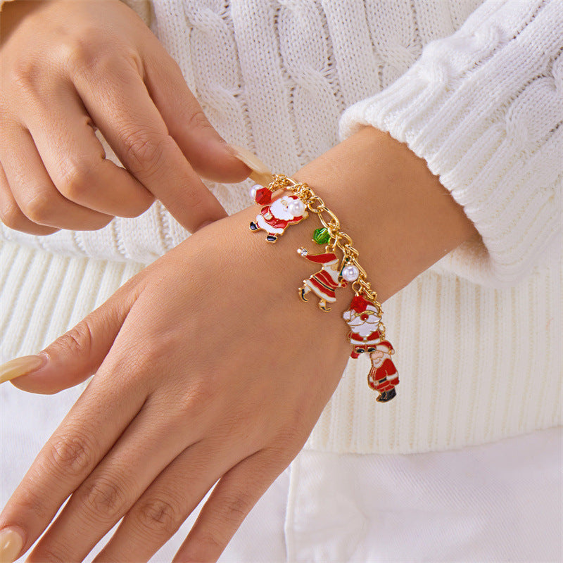 Bracciale artigianale in lega a tema natalizio con ciondolo a forma di Babbo Natale e albero di Natale, perline color caramella, accenti di perle e motivi a fiocco di neve festivi