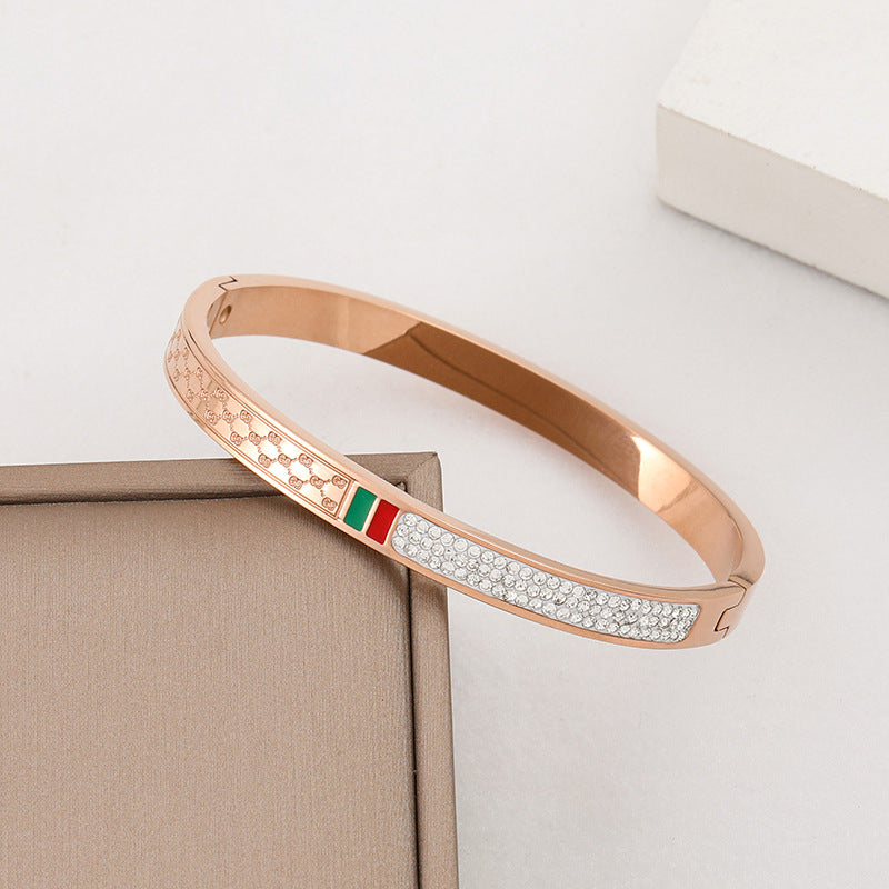 Pulsera minimalista de acero de titanio con incrustaciones de pedrería roja y verde, bañada en oro rosa para mujer