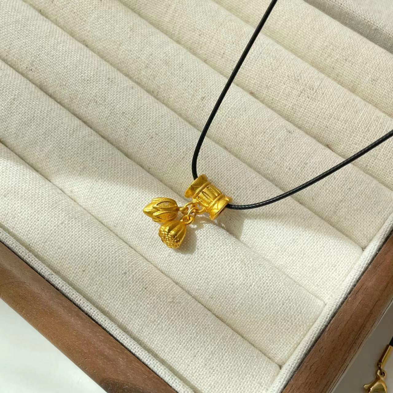 Collana con ciondolo a baccello di loto e zucca in stile etnico da donna con charm in rame placcato oro, dettaglio nappa, catena in cordino nero