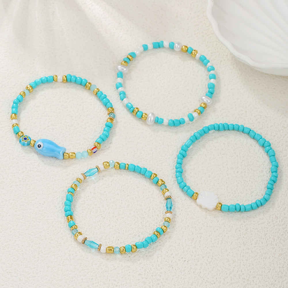 Pulsera bohemia de vacaciones en la playa con abalorios de peces y conchas de cerámica en un hilo de cuentas multicapa