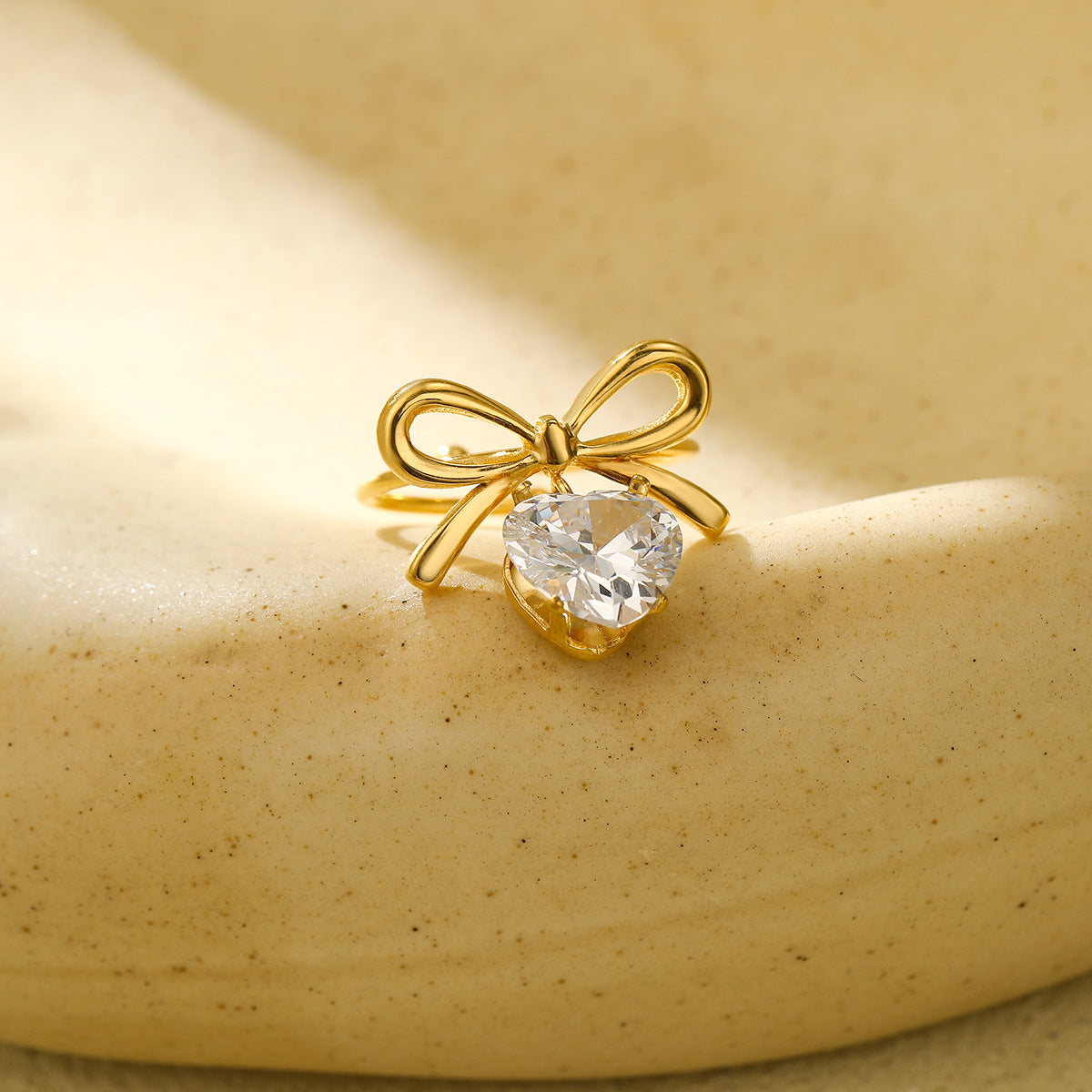 Anillo con colgante de corazón en forma de lazo estilo lujo para mujer, hecho de acero de titanio con incrustaciones de diamantes de imitación y acabado chapado