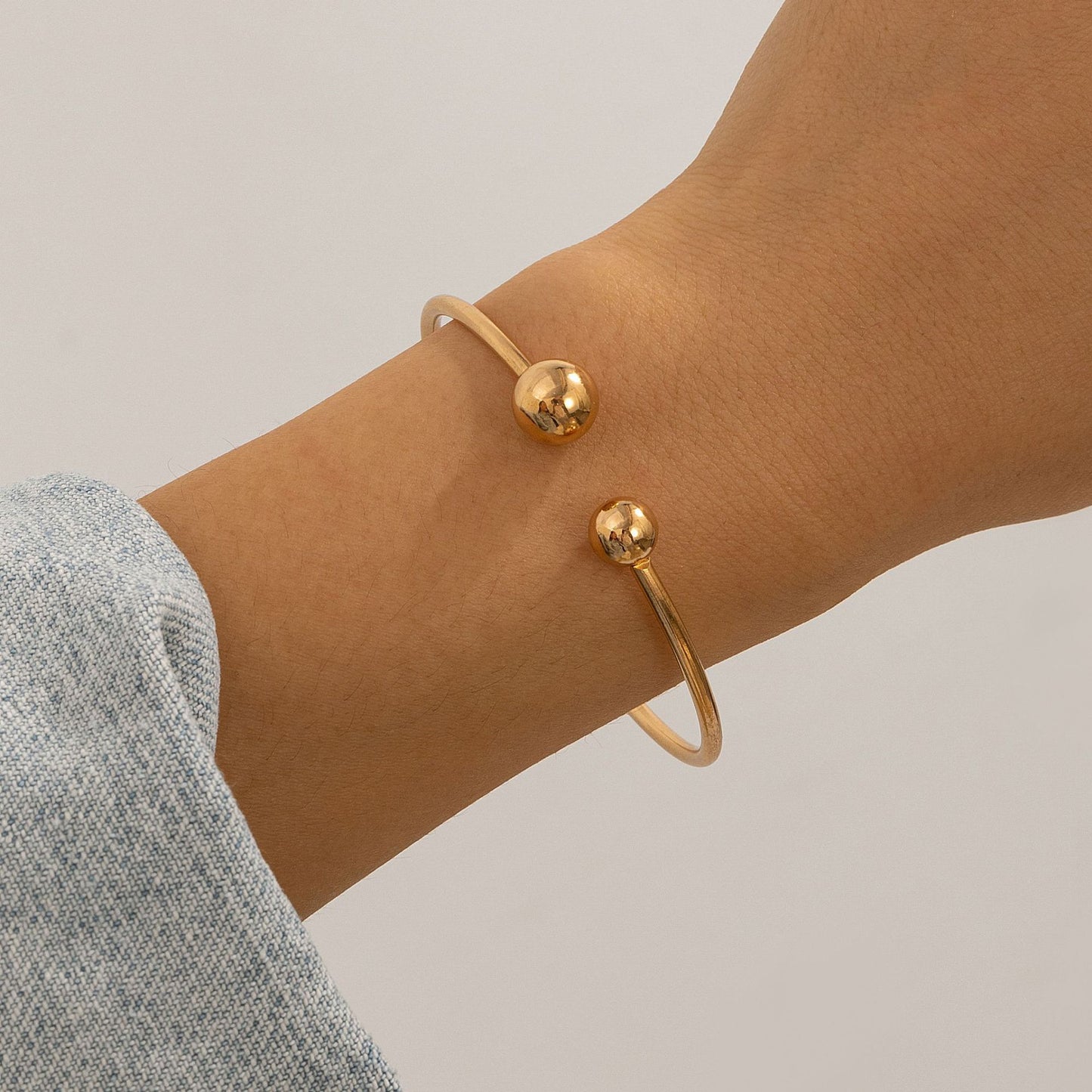 Brazalete abierto geométrico minimalista de doble capa con nudo hueco y acabado metálico chapado
