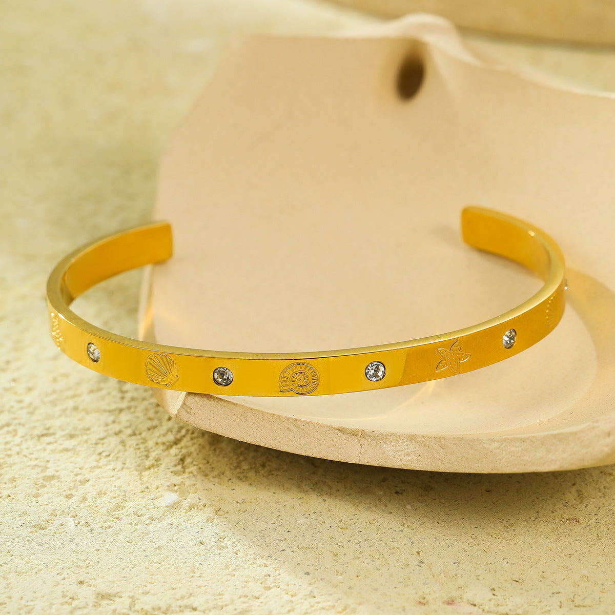 Brazalete abierto de acero de titanio con diseño geométrico, inspirado en el océano, con incrustaciones de pedrería y acabado chapado
