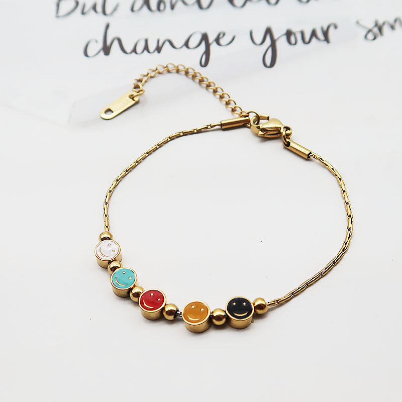 Bracciale da donna in acciaio al titanio con ciondolo sorridente minimalista, finitura smaltata e perline con accenti in oro 18 carati