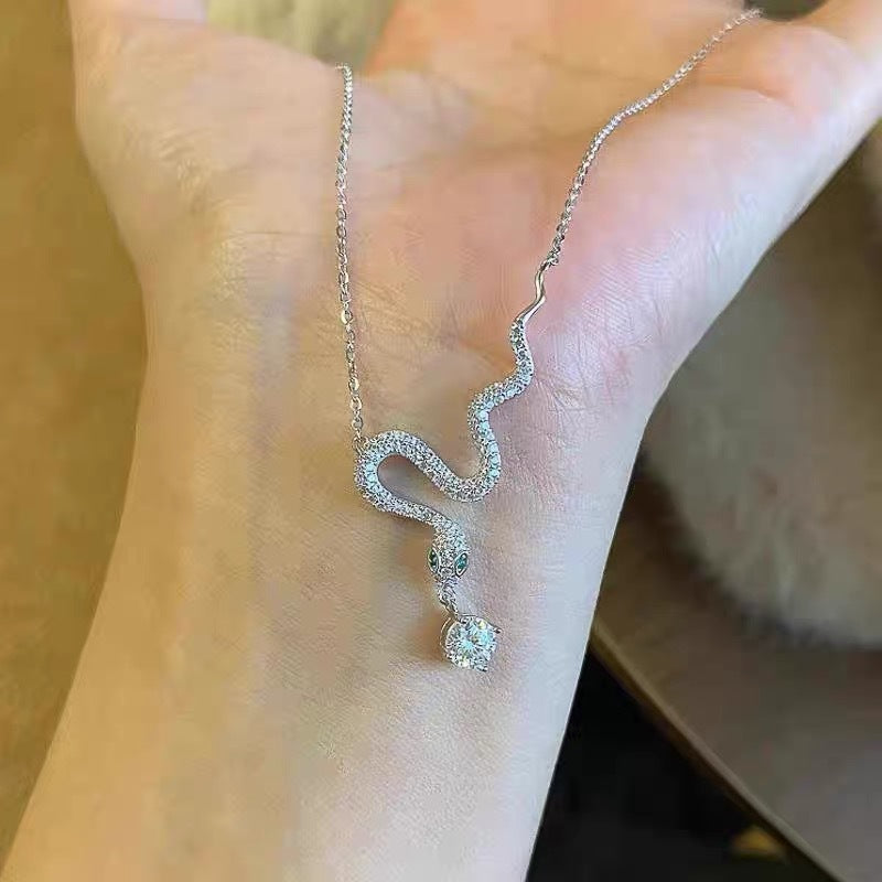 Collar con colgante geométrico minimalista en forma de serpiente de tono frío en acero de titanio con incrustaciones de pedrería y acabado chapado