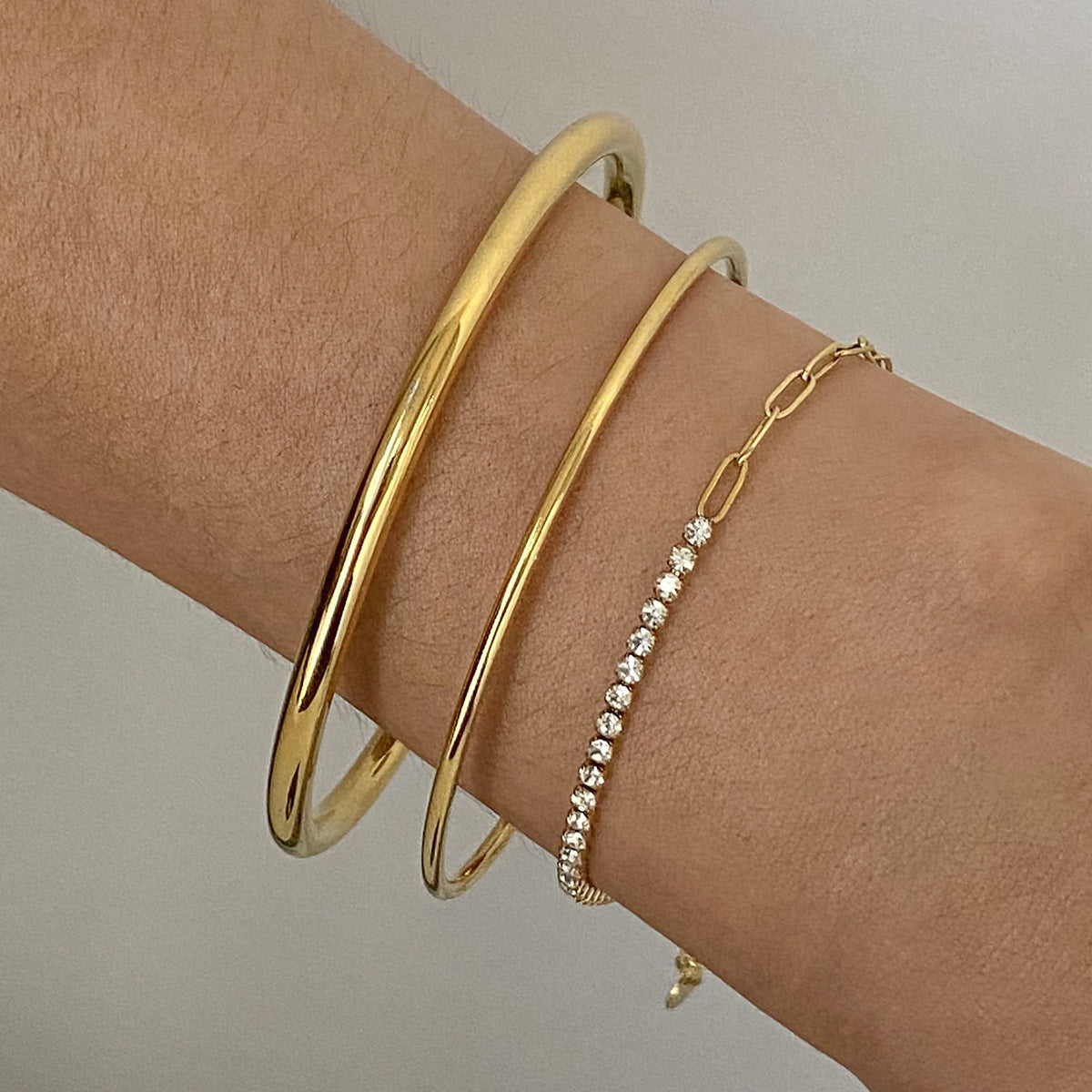 Brazalete minimalista de acero inoxidable con diseño geométrico, detalles de pedrería y acabado chapado