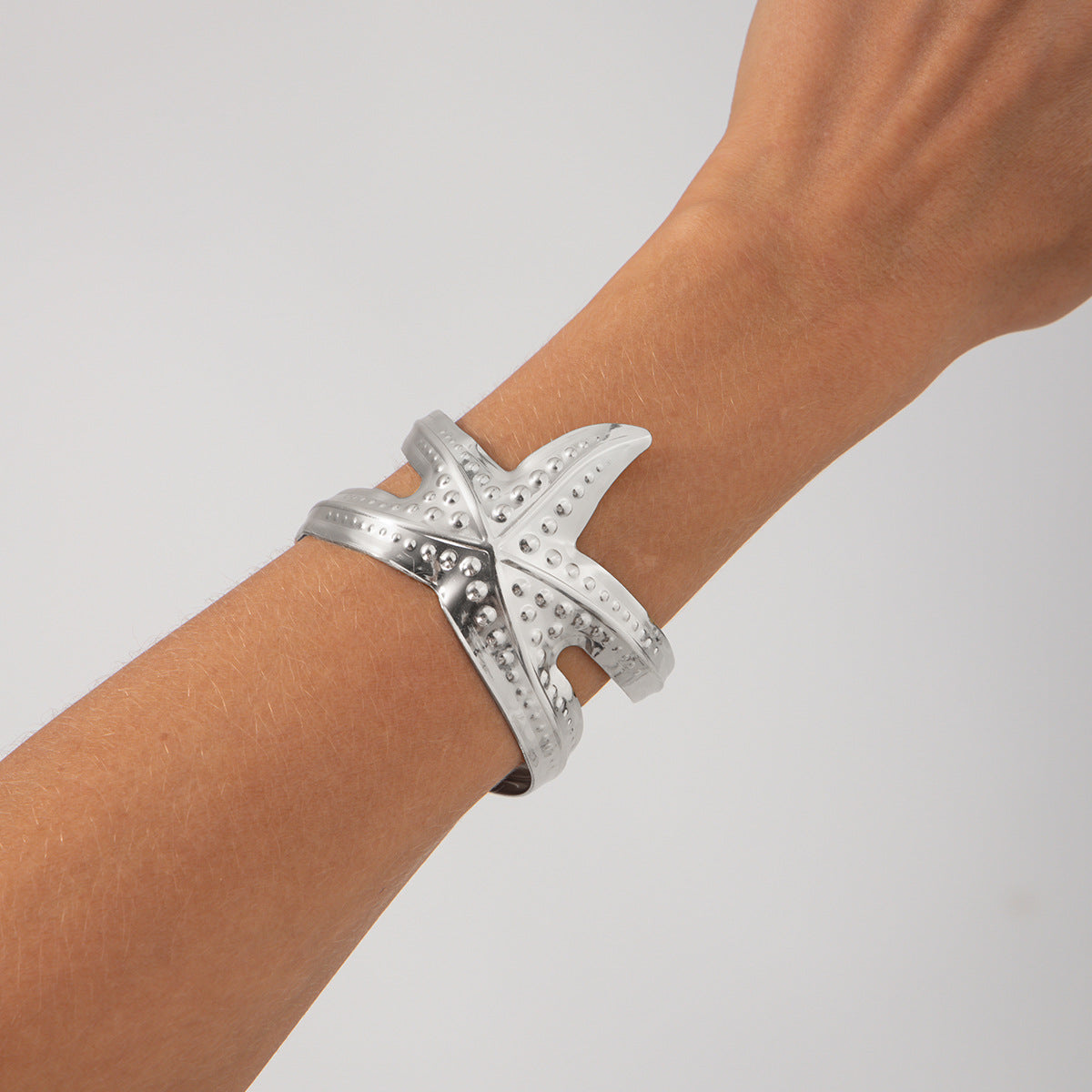 Pulsera metálica con forma de estrella de mar exagerada y acabado galvanizado para un estilo playero y oceánico