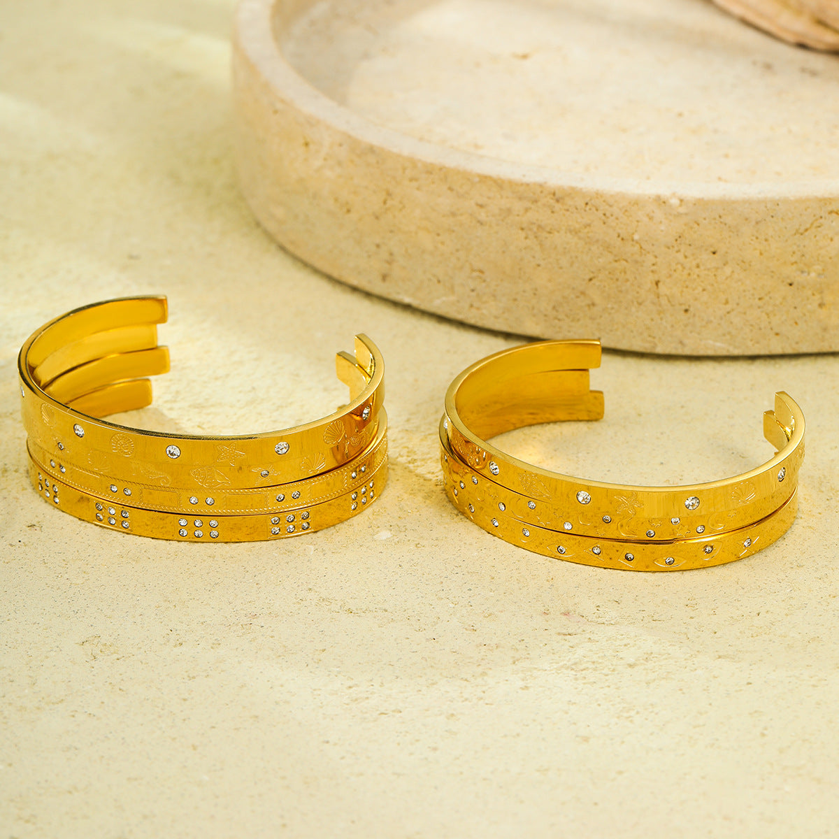Brazalete abierto de acero de titanio con diseño geométrico, inspirado en el océano, con incrustaciones de pedrería y acabado chapado