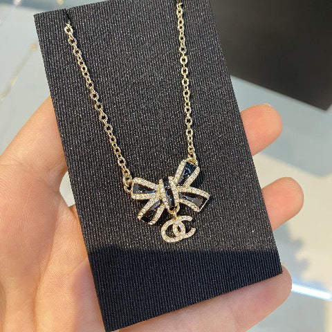 Elegante set di collana e orecchini in ottone placcato oro con fiocco smaltato da donna