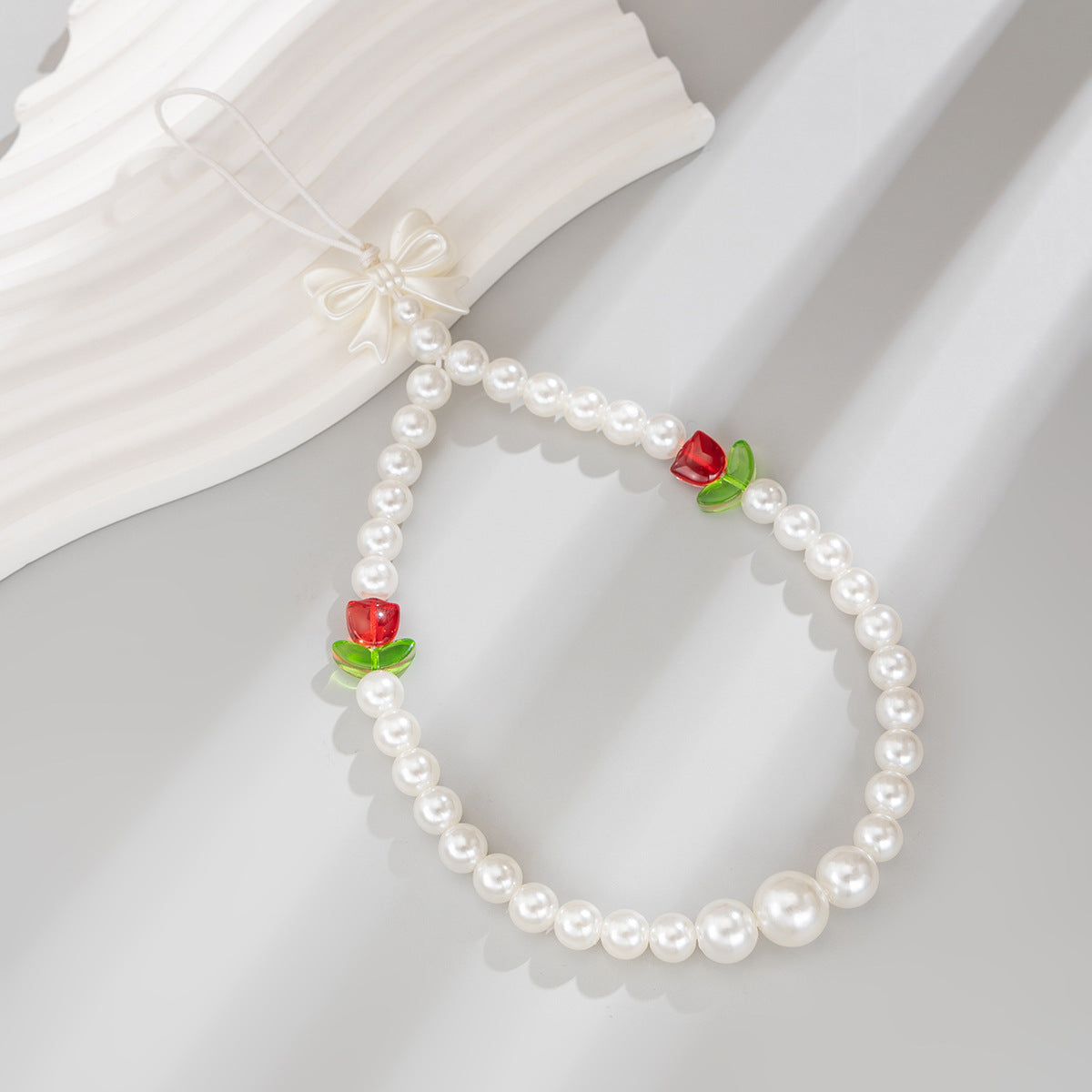 Bonita correa de teléfono con nudo de lazo de tulipán y perlas de imitación para mujeres, accesorio tejido a mano con dulce estilo floral