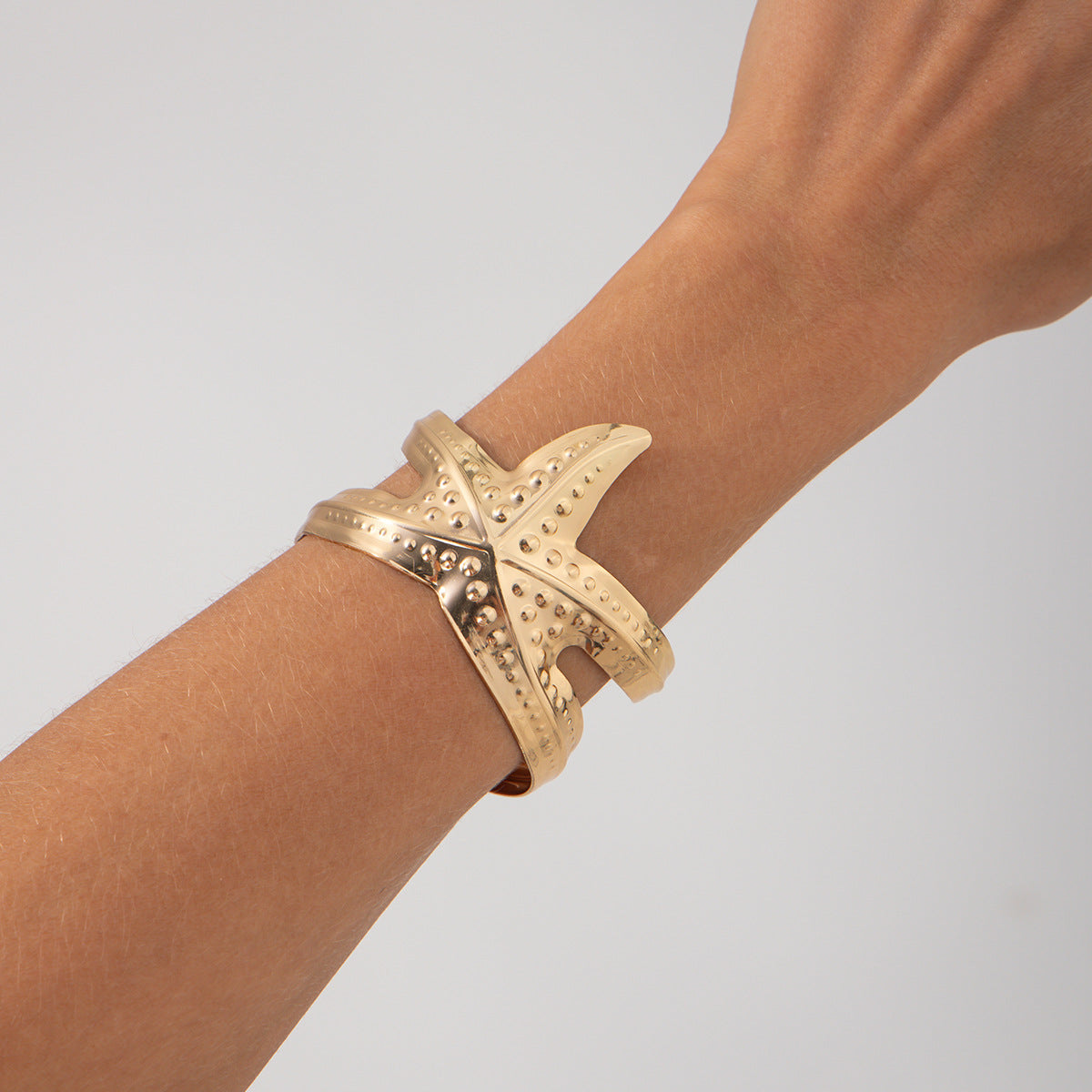 Pulsera metálica con forma de estrella de mar exagerada y acabado galvanizado para un estilo playero y oceánico
