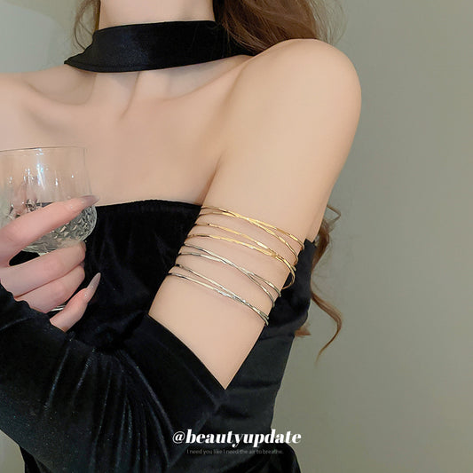 Bracciale rigido in metallo avvolto da linee geometriche irregolari, finitura placcata, stile minimalista, per un look da ufficio alla moda