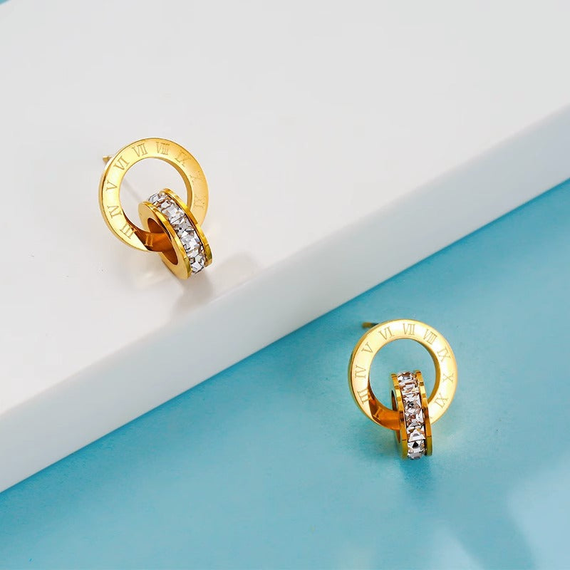 Orecchini a perno da donna in acciaio al titanio lucidato con doppio cerchio romano e strass, placcati in color oro e dallo stile fresco e grazioso