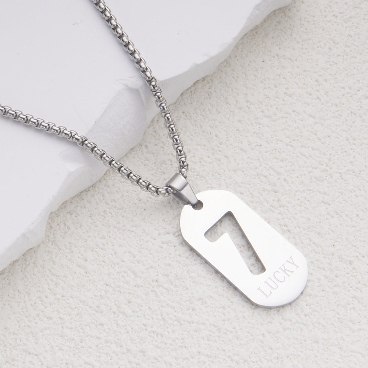 Collar con colgante minimalista del número de la suerte 7 en acero de titanio con acabado pulido para mujer y hombre