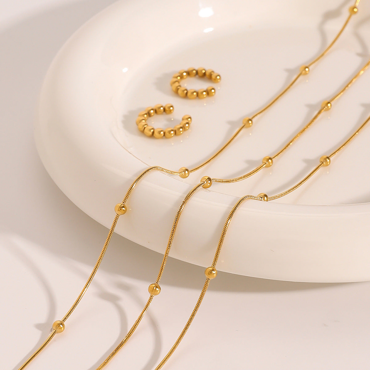 Collana da donna a più strati con perle dorate in acciaio inossidabile placcato e acciaio al titanio, con dettagli geometrici e linee delicate