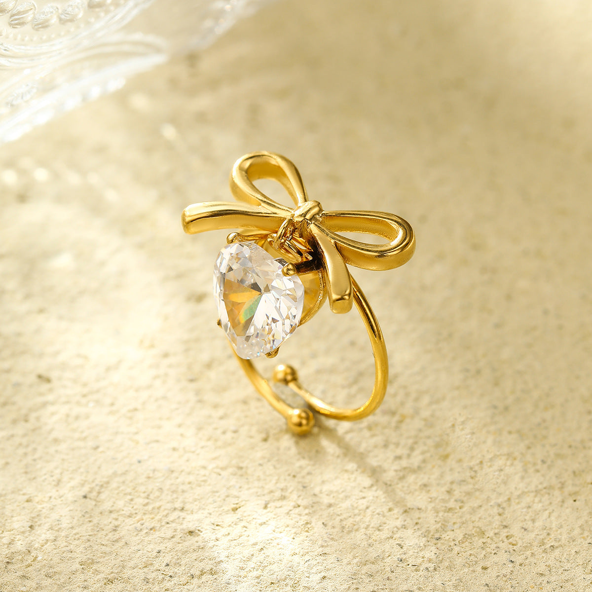 Anillo con colgante de corazón en forma de lazo estilo lujo para mujer, hecho de acero de titanio con incrustaciones de diamantes de imitación y acabado chapado