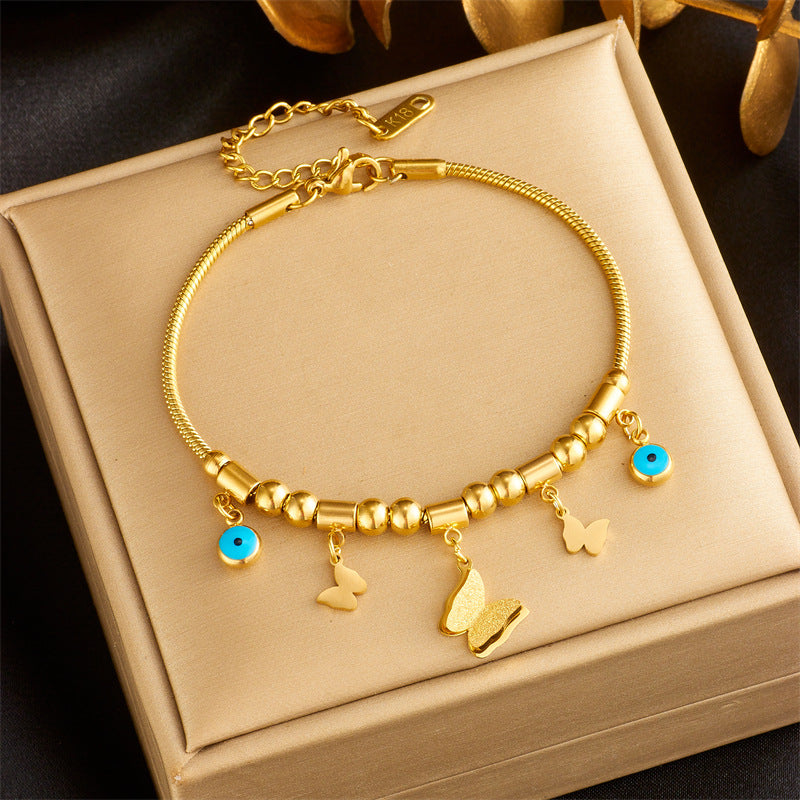 Elegante bracciale con ciondolo a farfalla in acciaio al titanio, perline geometriche e occhi smaltati blu per donna