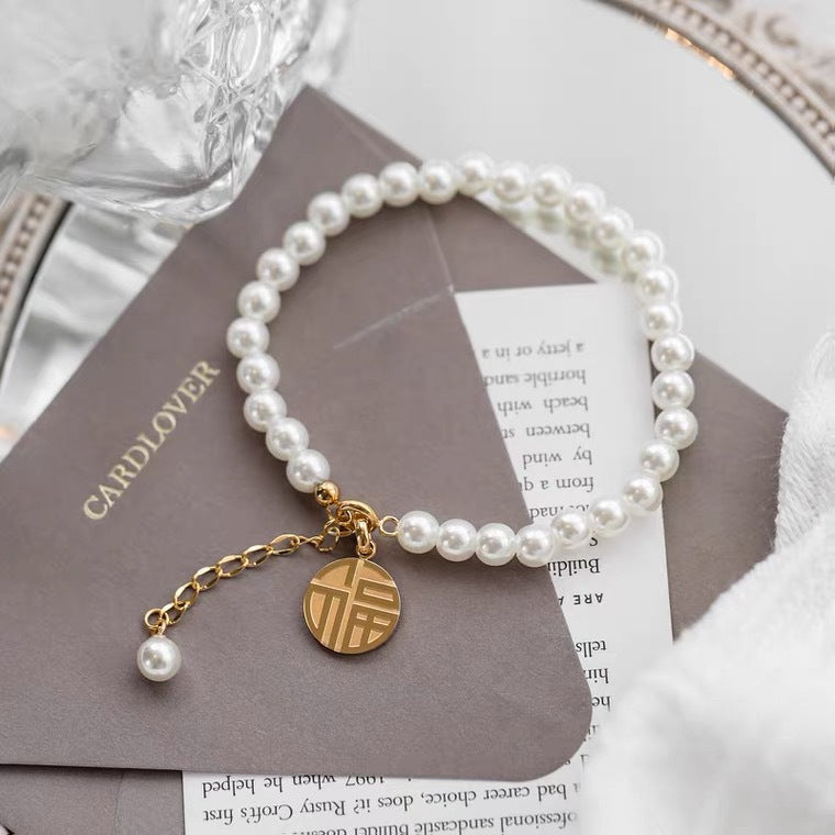 Bracciale minimalista geometrico in acciaio al titanio con pendente a carattere "Fu" placcato oro 18K e nappe di perle