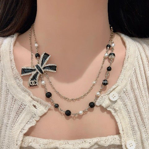 Elegante set di collana e orecchini in ottone placcato oro con fiocco smaltato da donna
