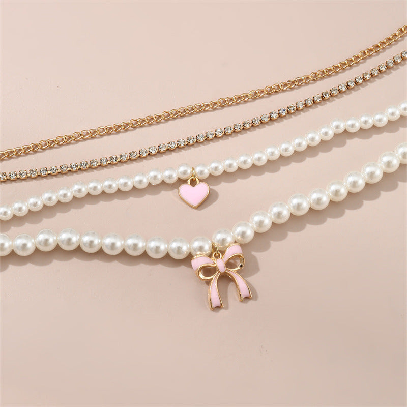 Set di collana con ciondolo a fiocco e cuore stile dolce per bambini con accenti di perle e perline infilate a mano su catena in resina
