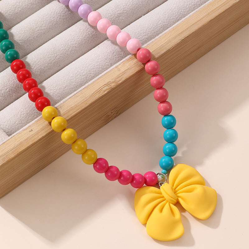 Lindo Collar de Resina con Forma de Lazo para Niñas con Acabado Pintado en Diseño Multicolor, Joyería Infantil Dulce y Juguetona
