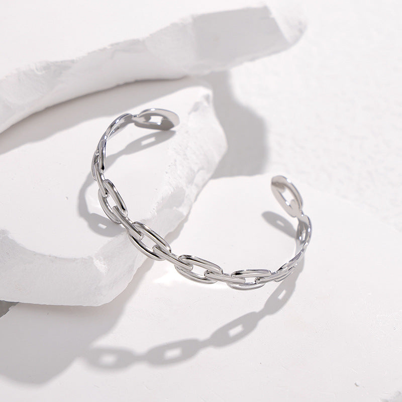 Pulsera Minimalista de Acero de Titanio Abierta para Mujer con Acabado Chapado y Detalle de Cadena