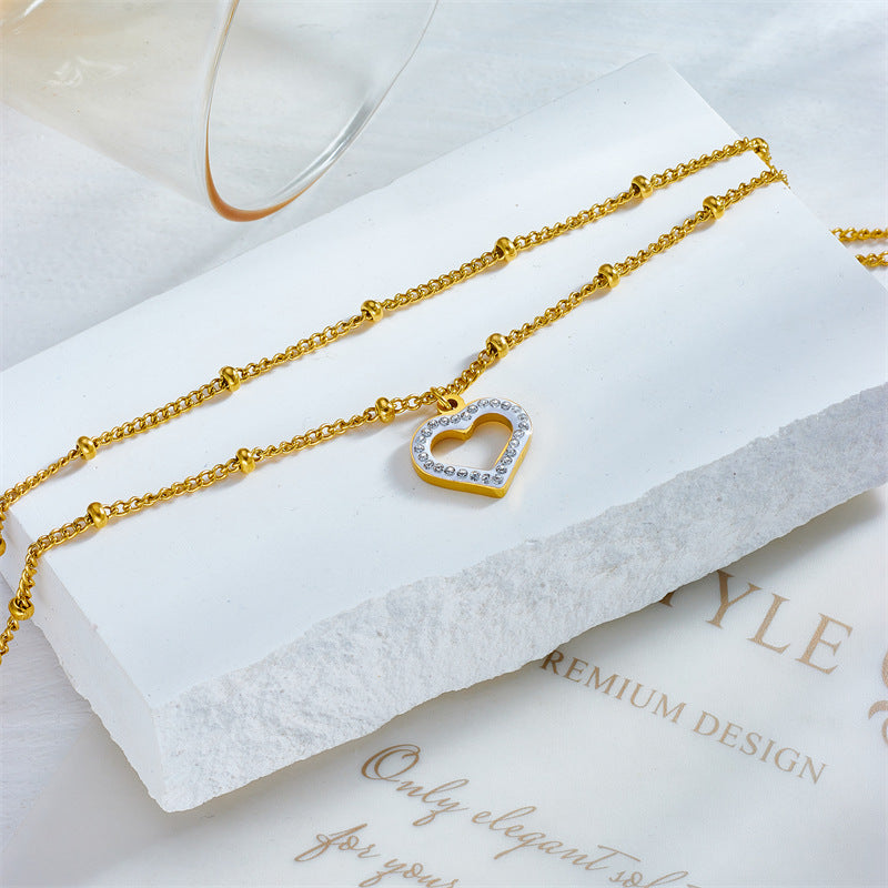 Cavigliera minimalista in acciaio al titanio a forma di cuore con intarsio di strass e design a doppia catena