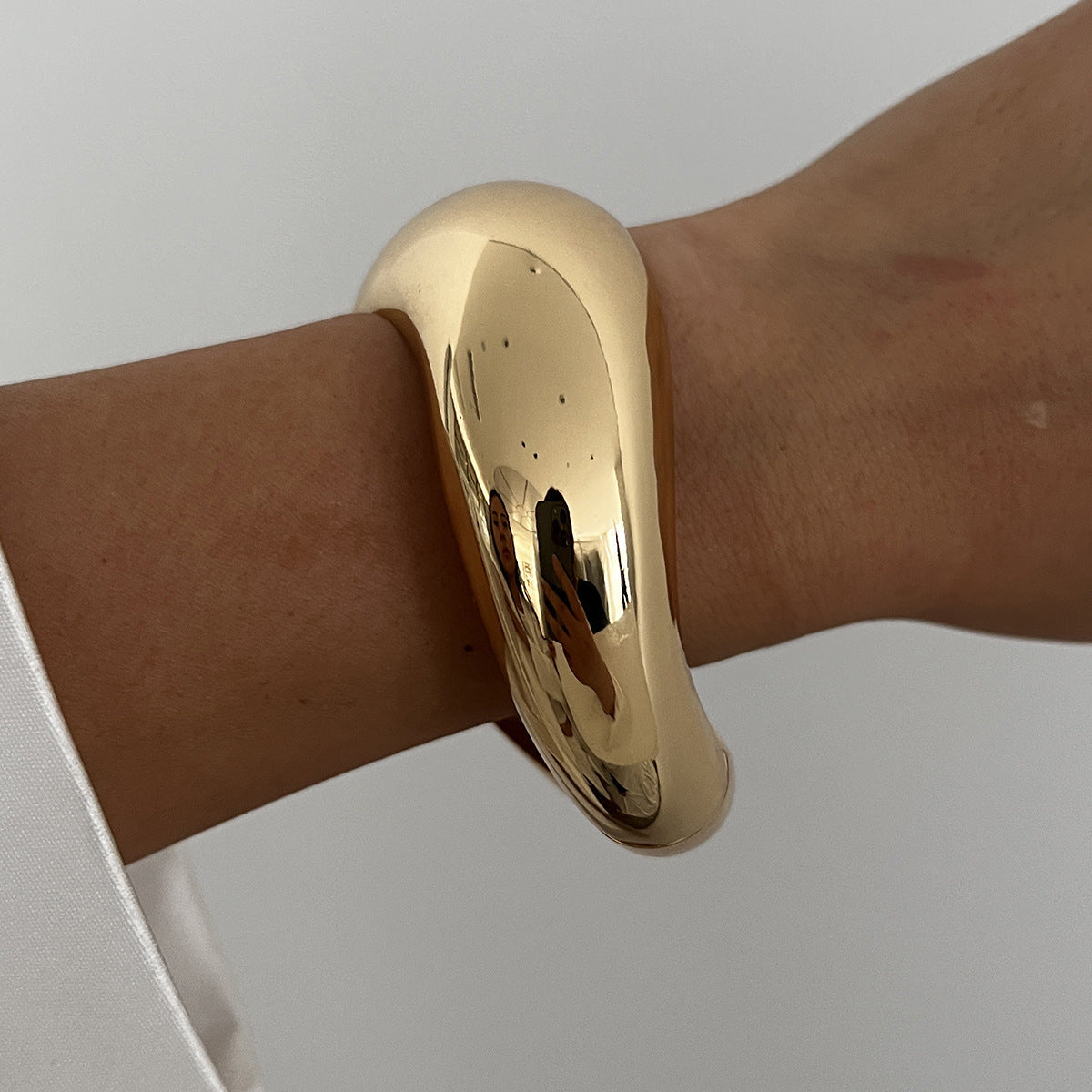 Bracciale rigido da donna in metallo audace con design geometrico, superficie lucida e finitura placcata